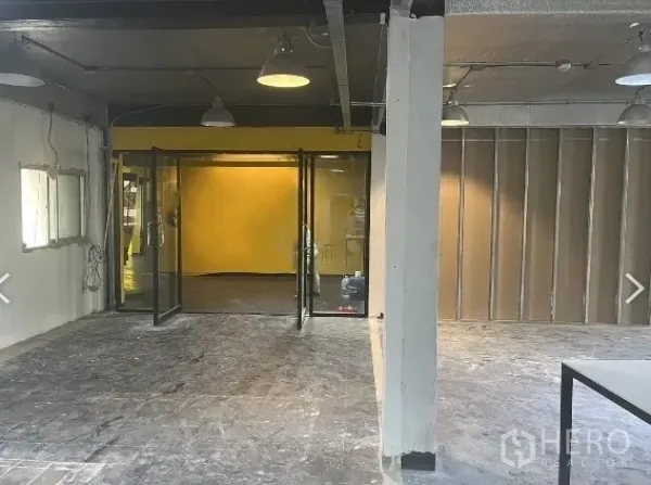 Retail Space for rent in Pathum Wan, Bangkok - Shell retail interior with glass double doors, yellow feature wall, exposed lights and columns.