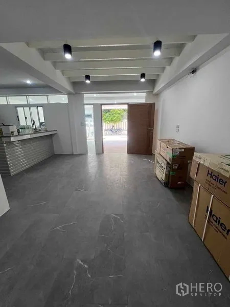 Townhouse for rent in Khlong Toei, Bangkok - Open-plan ground floor living area with dark tile floors and adjacent kitchen.