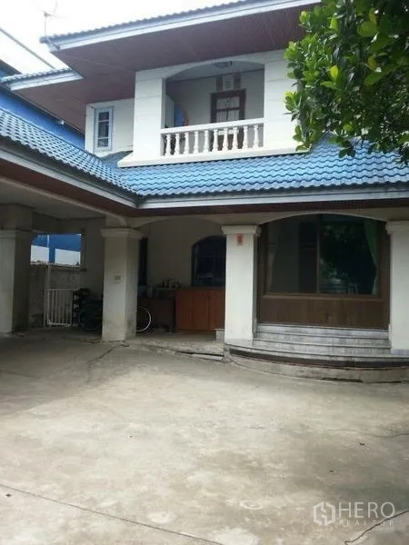Detached House for rent in Bang Na, Bangkok - Front exterior with curved bay window and a wide concrete driveway for multiple cars.