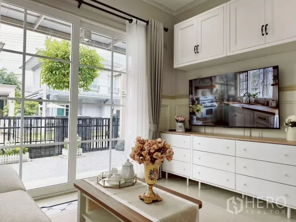 Detached House for rent in Khlong Luang, Pathum Thani - Living room with TV console and coffee table facing glass doors to the patio