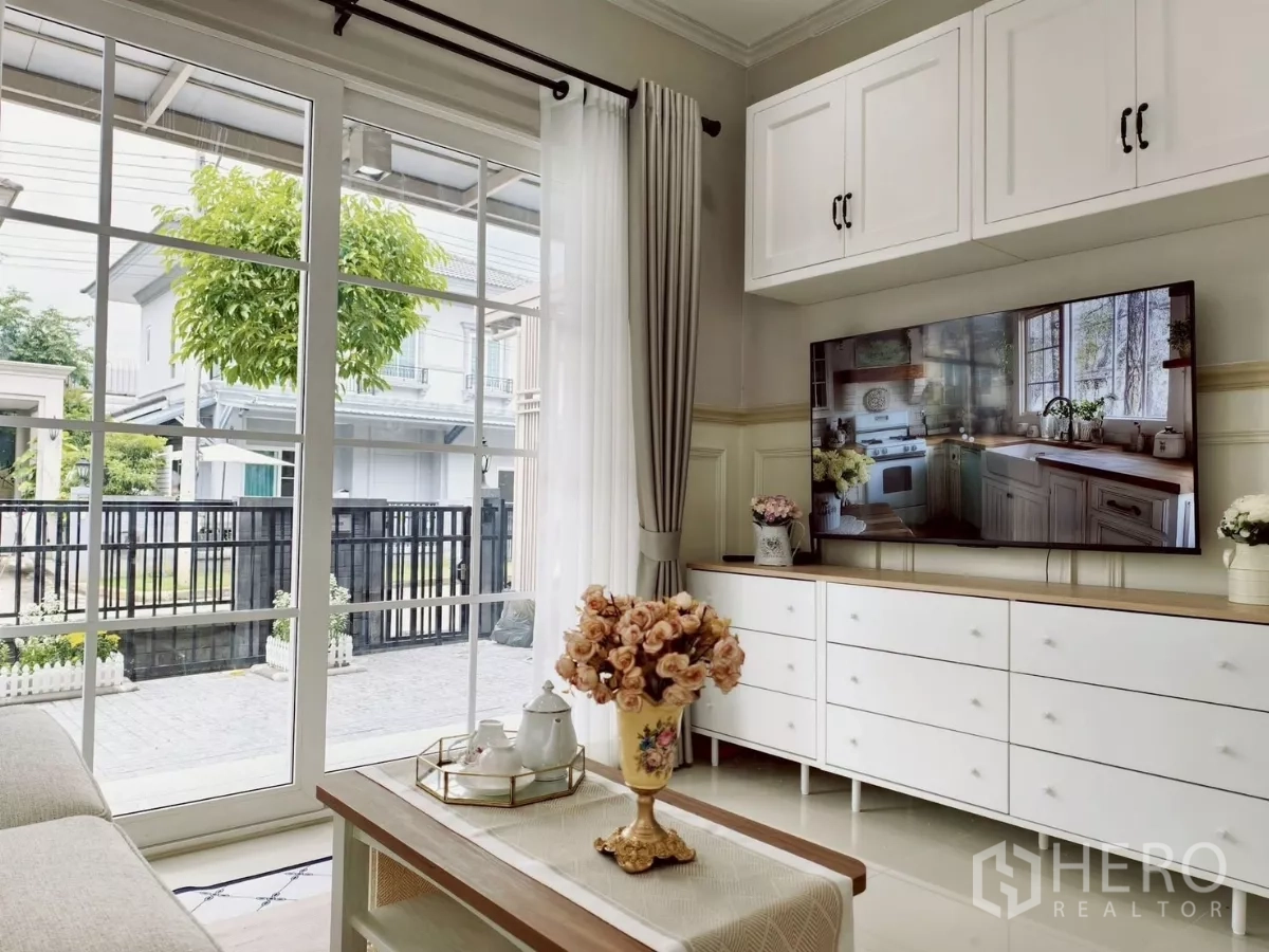 Detached House for rent in Khlong Luang, Pathum Thani - Living room with TV console and coffee table facing glass doors to the patio