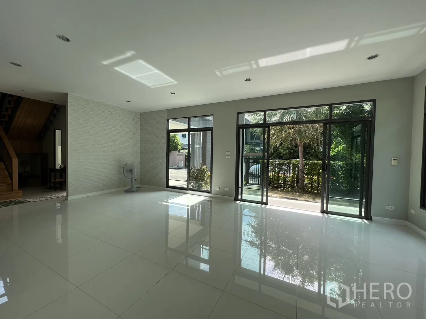 独立式住宅 出售在Suan Luang, Bangkok - 客厅一角可见楼梯与多扇玻璃门，引入自然光。