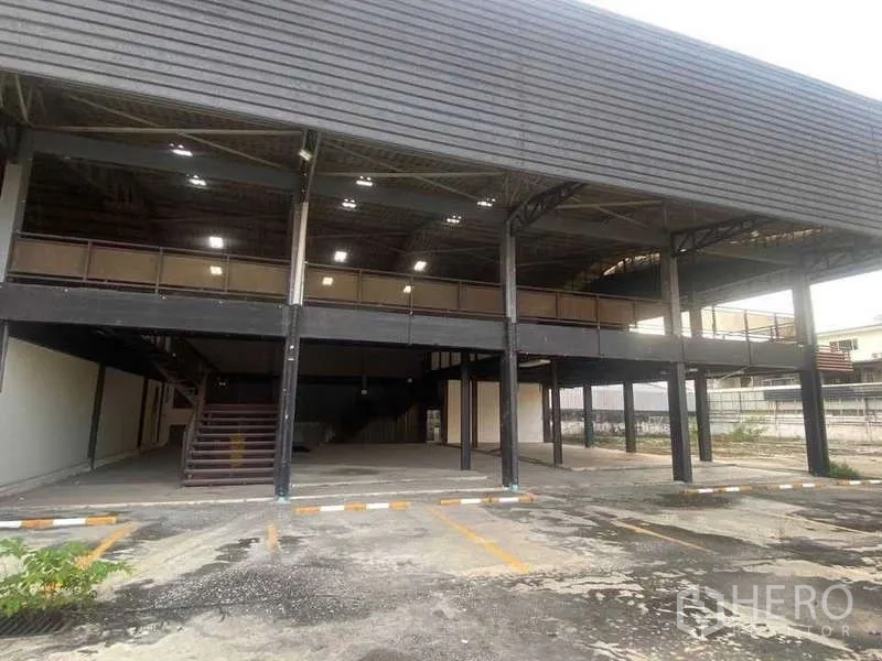 Warehouse for rent in Phra Khanong, Bangkok - Front facade of the warehouse with twin staircases, lit undercroft and on-site parking bays.