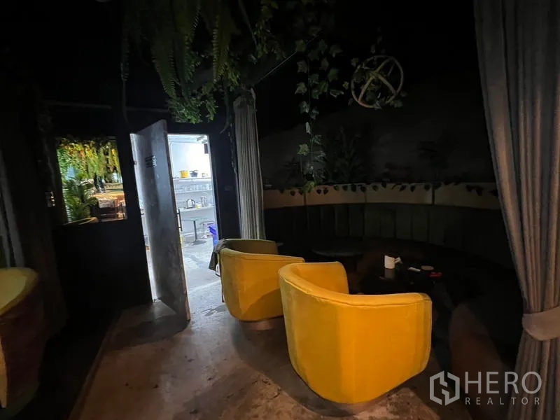 Retail Space for rent in Watthana, Bangkok - Dark lounge room with yellow armchairs, round table, and draped partitions.