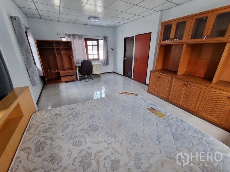 Detached House for rent in Nonthaburi - Master bedroom featuring built-in wardrobe, desk, and doors to ensuite/storage.