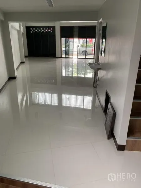 Shophouse for rent in Suan Luang, Bangkok - Open-plan ground floor retail space with high-gloss tiles, storefront windows and a wall-mounted sink.