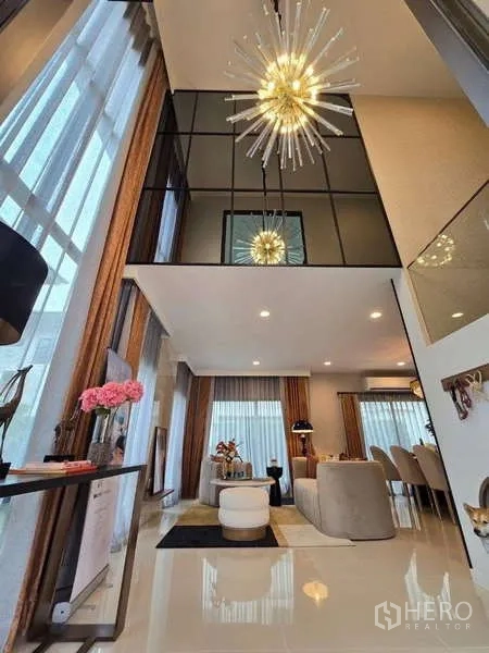 Detached House for rent in Bang Kapi, Bangkok - Double-height living room with statement chandelier and floor-to-ceiling windows.