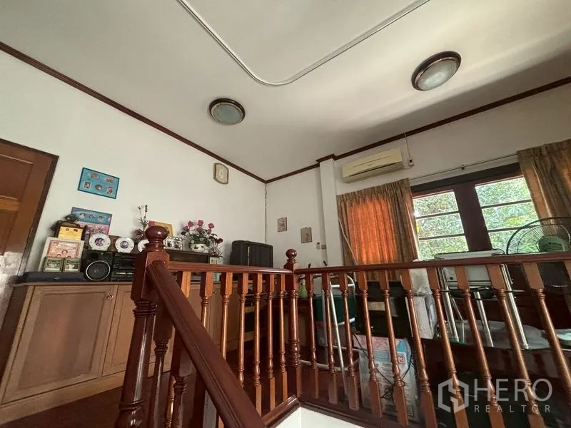 Detached House for sale in Suan Luang, Bangkok - Upstairs nook with wooden railing, cabinets and air conditioner.