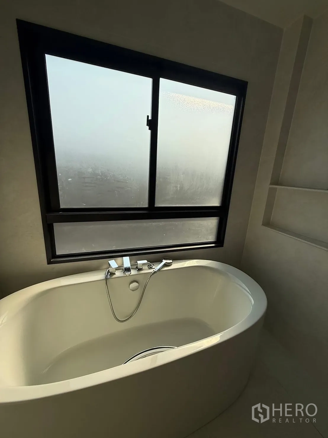 Detached House for rent in Bang Kapi, Bangkok - Modern bathroom featuring a freestanding bathtub beneath a large frosted window.