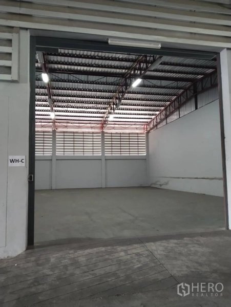 Warehouse for rent in Lat Krabang, Bangkok - Wide warehouse bay labeled WH-C with roller door, concrete floor, and ventilated louver panels.