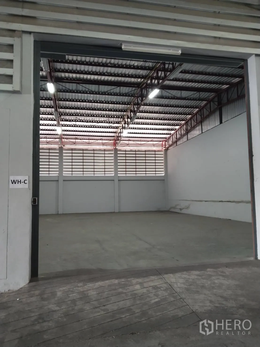 Warehouse for rent in Lat Krabang, Bangkok - Wide warehouse bay labeled WH-C with roller door, concrete floor, and ventilated louver panels.