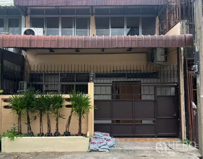 Townhouse for rent - Two‑storey townhouse frontage with gated carport and potted palms in Bang Chak.