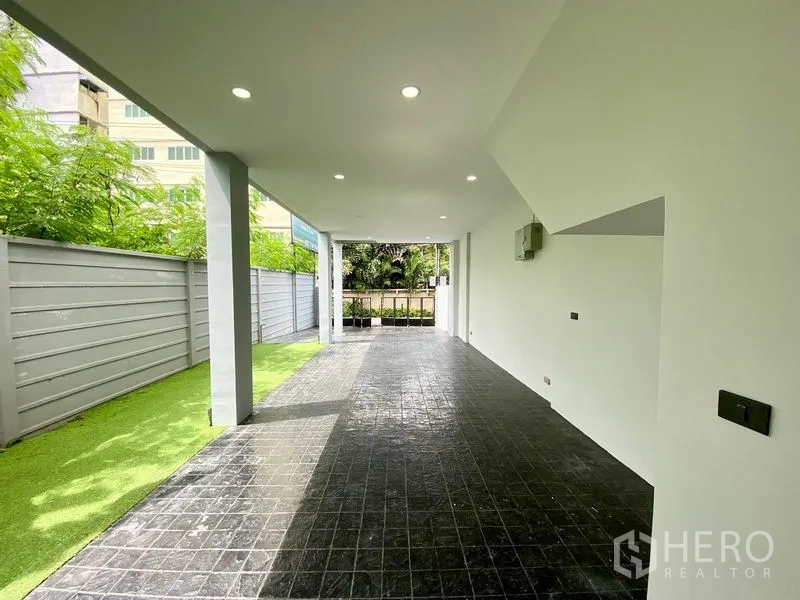 Home Office for rent or sale in Bang Na, Bangkok - Covered carport with tiled floor and a strip of artificial grass along the fence at a modern Bang Na home office.