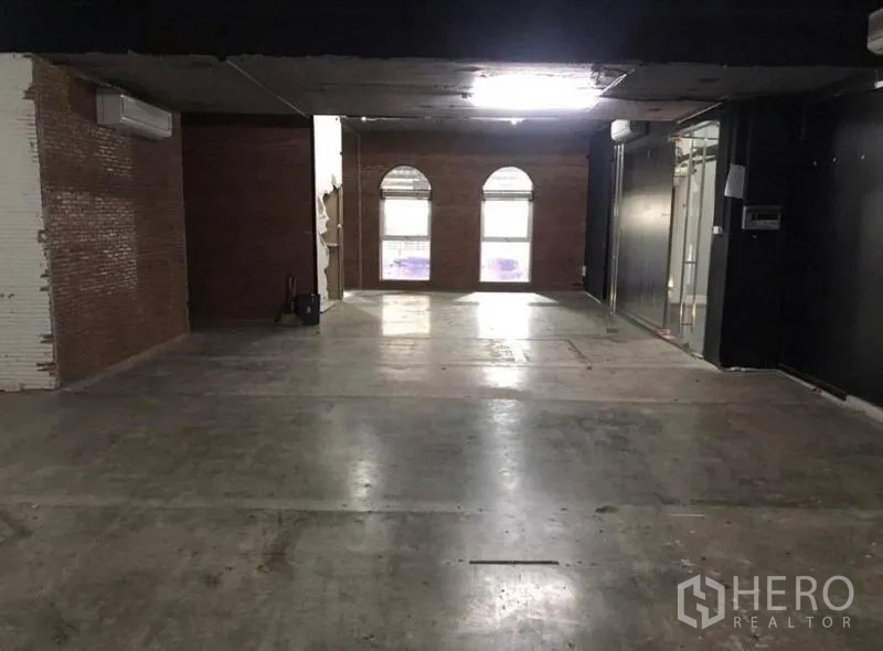 Office Space for rent in Watthana, Bangkok - Industrial-style workspace featuring brick accent wall and arched windows.