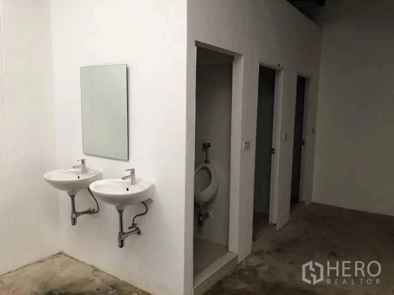 Factory for rent or sale in Bang Phli, Samut Prakan - Factory restrooms featuring twin wall-mounted sinks and separate toilet stalls.
