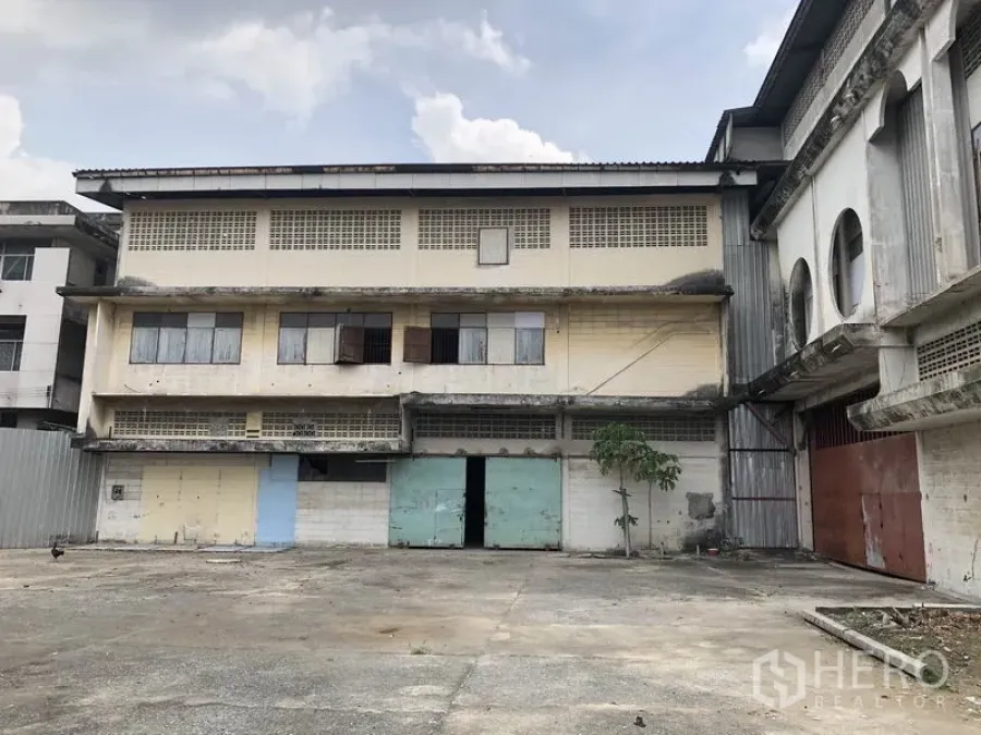 Warehouse for rent in Lak Si, Bangkok - Three-storey warehouse facade with loading doors and a wide concrete yard in Lak Si, Bangkok.