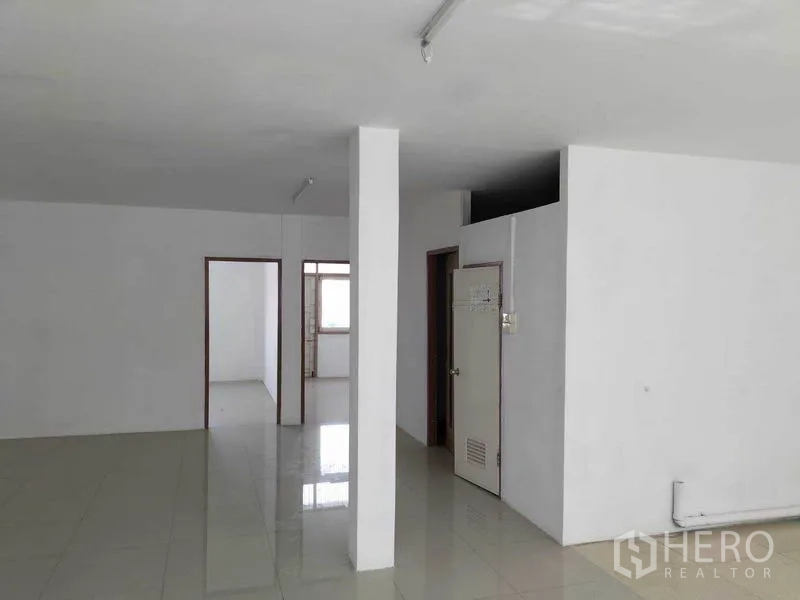 Shophouse for rent in Khlong Toei, Bangkok - Bright open floor with tiled surface, white columns and an internal bathroom enclosure.