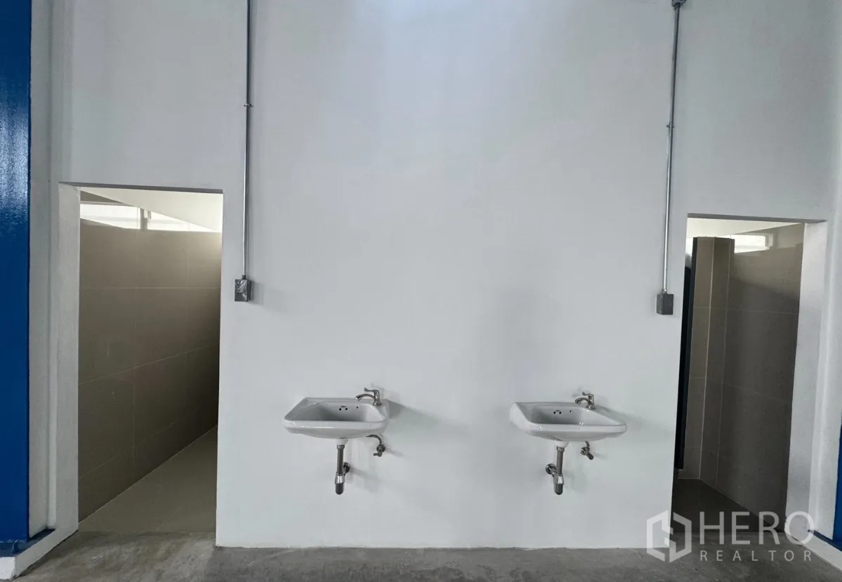 Warehouse for rent in Khlong Luang, Pathum Thani - Wash area with two wall-mounted sinks and entrances to restrooms.