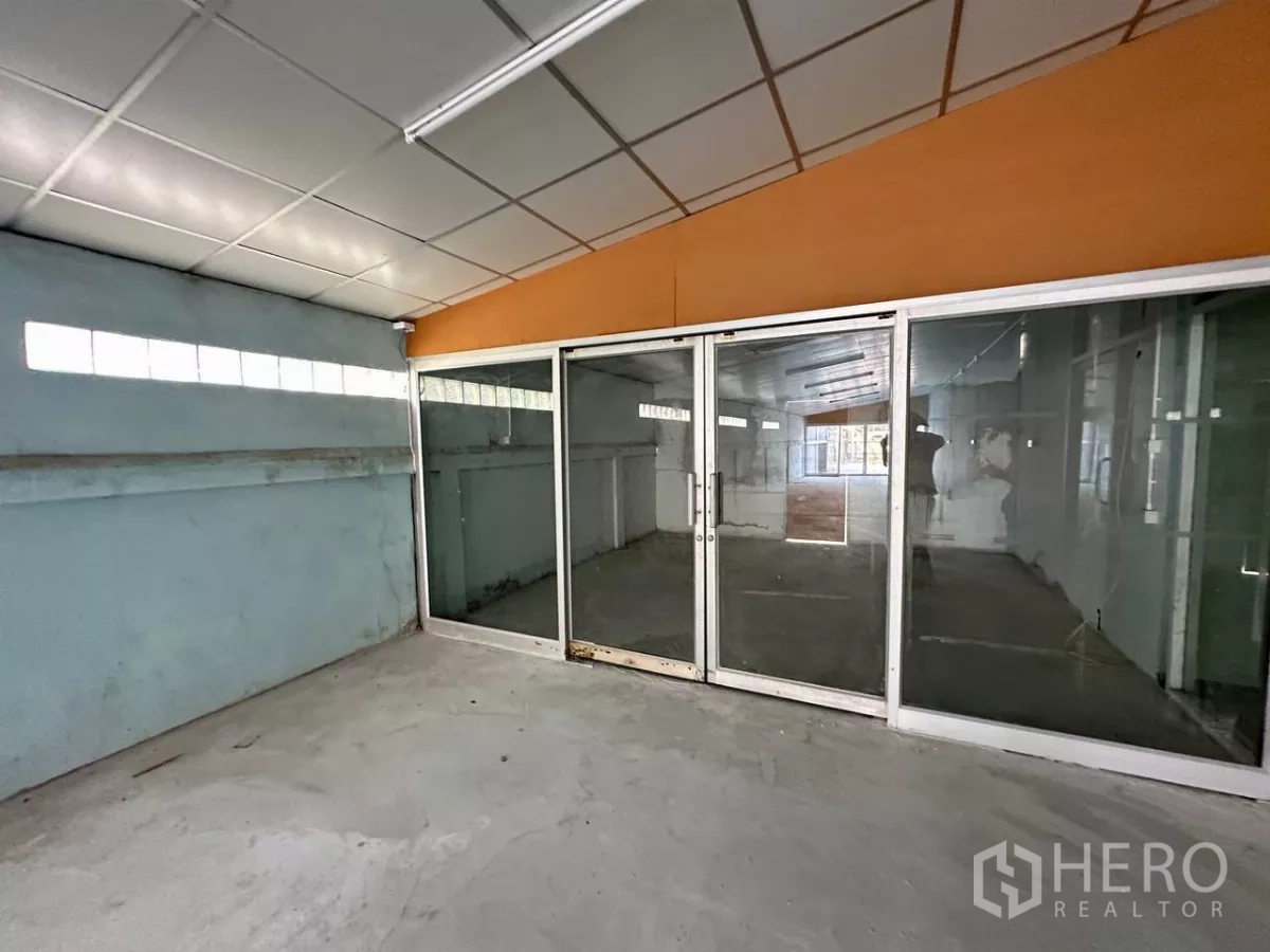 Factory for rent in Samut Prakan - Enclosed workspace with sliding glass doors and tiled ceiling.