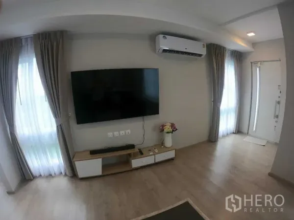 联排别墅 出租 - 客厅明亮，墙挂电视、空调、窗帘与浅木地板。