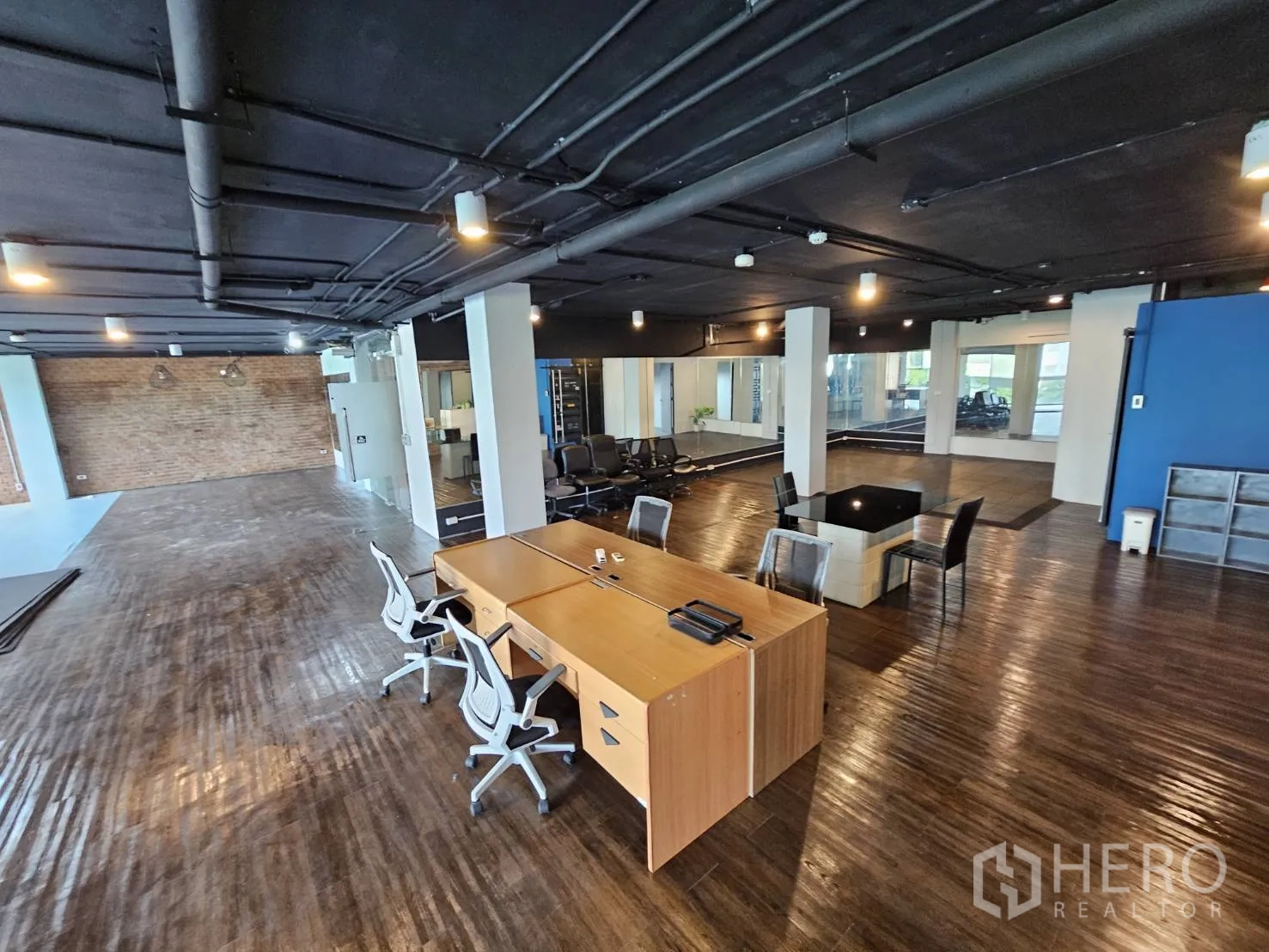 Office Space for rent in Watthana, Bangkok - Collaborative work zone with wooden floor, exposed ceiling piping, desks and seating clusters.