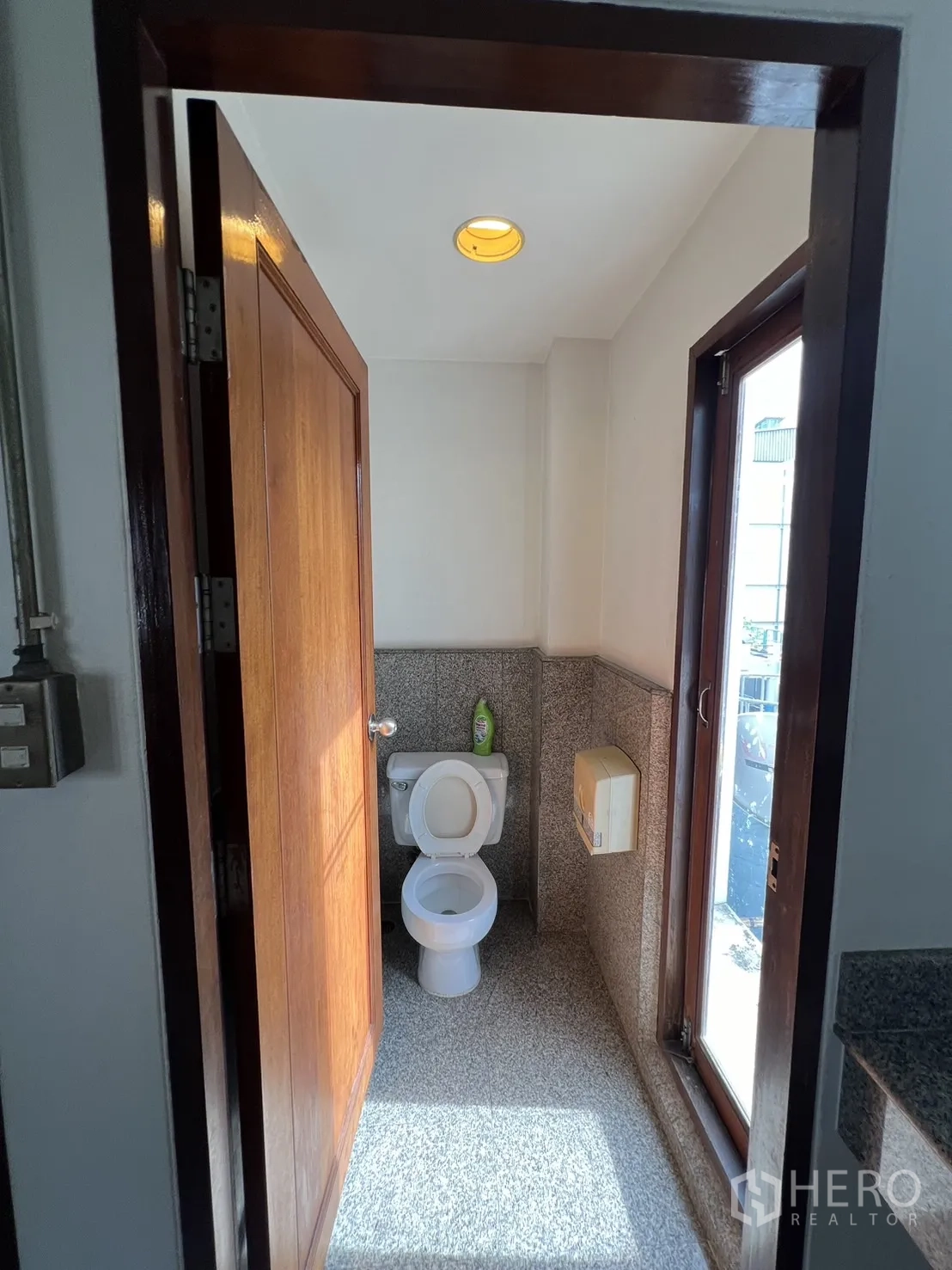 Home Office for rent in Watthana, Bangkok - Small restroom with window, granite-style floor and wooden door.