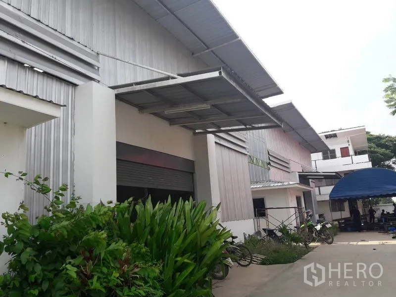 Warehouse for rent or sale in Khlong Luang, Pathum Thani - Exterior view of warehouse units with covered loading bays and driveway access.