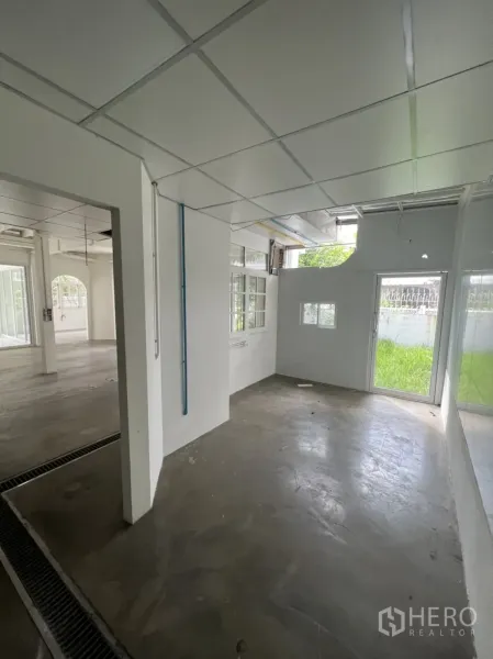 Detached House for rent or sale in Sathon, Bangkok - Bright side room with large windows, concrete floor and sliding door opening to greenery.
