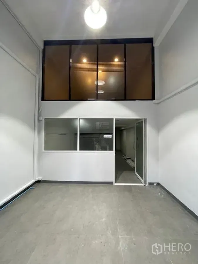 Home Office for rent in Chatuchak, Bangkok - Double-height entry space with glass mezzanine and office partition in a Chatuchak home office.
