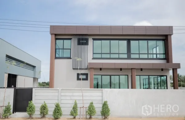 Factory for rent or sale in Nakhon Pathom - Front elevation of the office facade behind a low wall with young landscaping.
