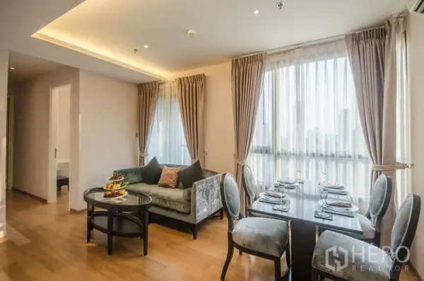 Condominium for rent or sale in Watthana, Bangkok - Bright living and dining area with floor-to-ceiling windows, curtains and hardwood floors in a modern Bangkok condo.