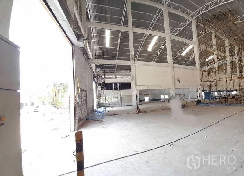 Factory for rent in Mueang Samut Prakan, Samut Prakan - Spacious factory interior with high steel trusses, LED strip lights and a wide loading door.