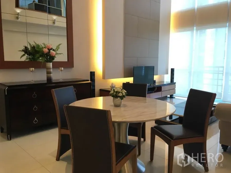 Condominium for rent in Pathum Wan, Bangkok - Contemporary living and dining area with a round marble table, TV console and warm accent lighting.