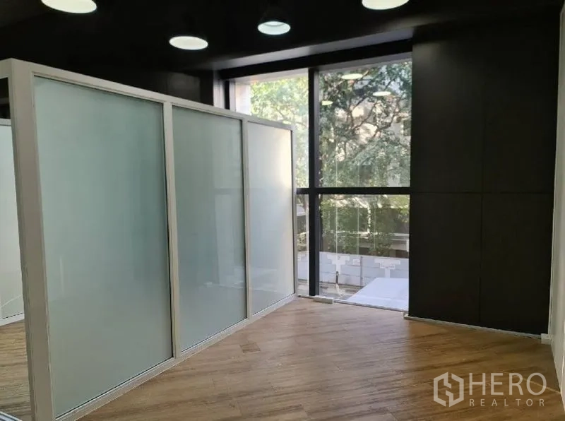Office Space for rent - Corner area with movable frosted divider panels beside tall windows.