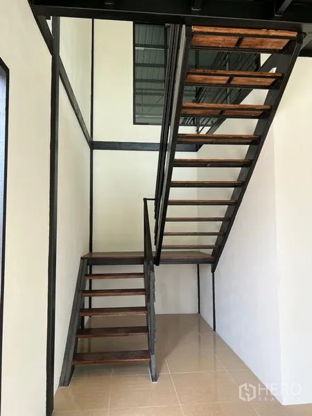Warehouse for rent in Lam Luk Ka, Pathum Thani - Steel-and-wood staircase leading to the mezzanine office inside the warehouse.