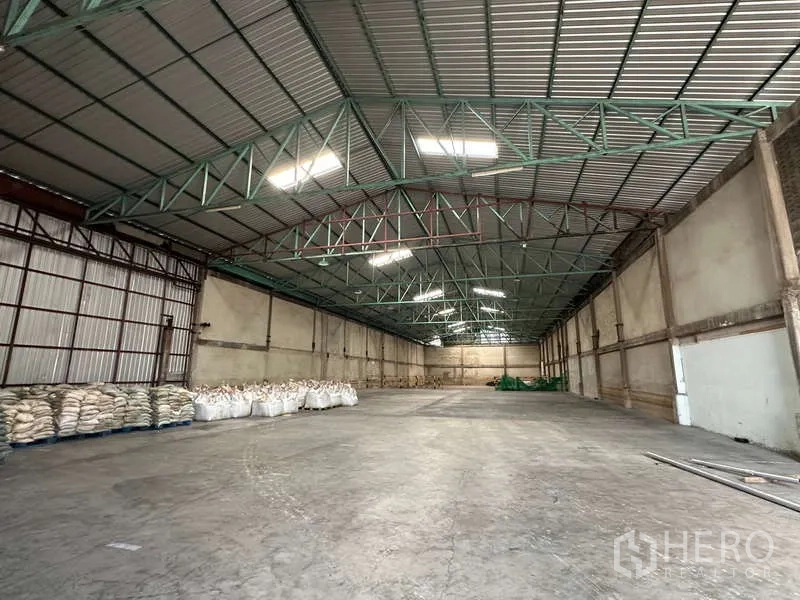 Warehouse for rent in Mueang Pathum Thani, Pathum Thani - Clear-span warehouse bay with insulated roof and palletized goods along the wall.