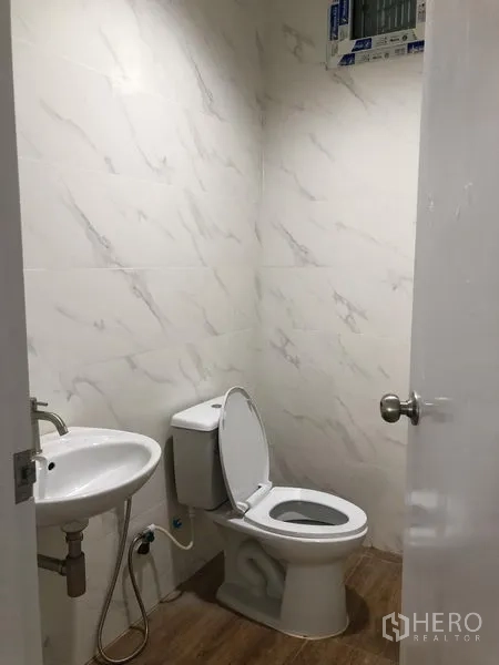 Factory for rent in Samut Prakan - Clean restroom with toilet, basin and tiled walls.