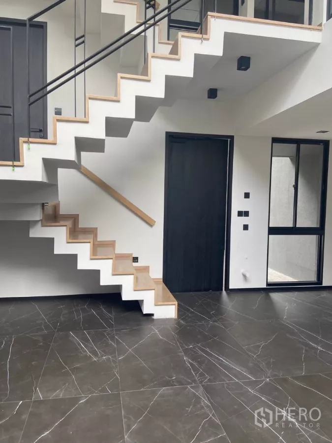 Townhouse for rent in Huai Khwang, Bangkok - Contemporary floating staircase with wood treads above glossy black marble tiles.