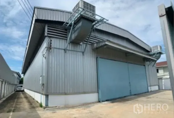 货栈 出租在Suan Luang, Bangkok - 金属板外墙的仓库外观，带大双开门、通风管道与车道。