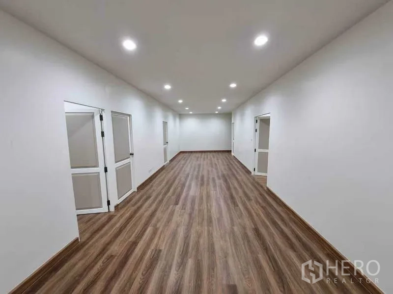 Shophouse for rent in Bang Rak, Bangkok - Corridor-like workspace with wood floors, side doors to private rooms and evenly spaced downlights.