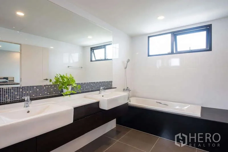 Detached House for rent or sale in Kanchanaburi - Contemporary bathroom with double vanity, bathtub, and a wide mirror.
