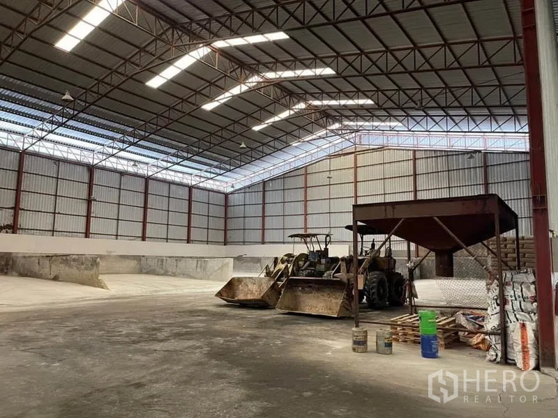 Warehouse for sale in Lam Luk Ka, Pathum Thani - High-clearance bulk storage hall featuring skylights, concrete partitions, and loaders.