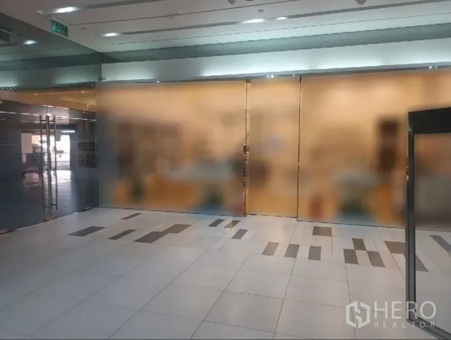 Retail Space for rent in Khlong Toei, Bangkok - Wide glass-fronted retail unit with double doors opening to a bright tiled mall corridor in Bangkok.