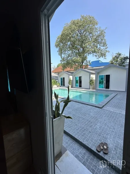 Home Office for rent in Suan Luang, Bangkok - Swimming pool seen from doorway with tiled terrace and large tree.