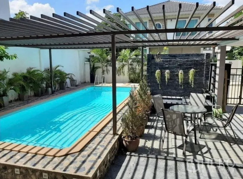 Detached House for sale in Bang Phli, Samut Prakan - Sunny pool terrace with pergola, outdoor dining set and a stone water feature wall.