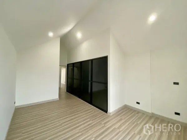 Home Office for rent or sale in Bang Na, Bangkok - Bright room with high sloped ceiling, wood-look flooring and a black framed glass partition wall.