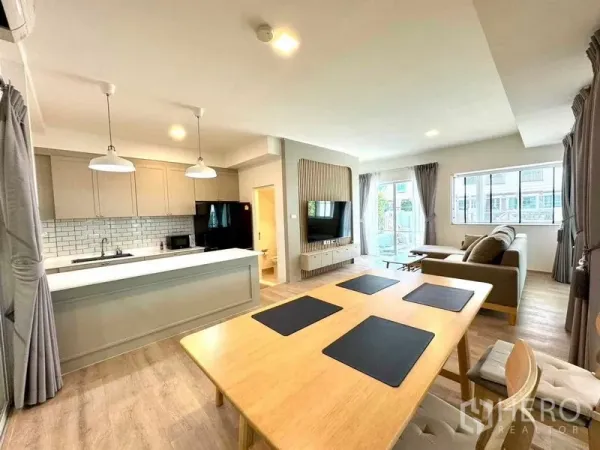 Townhouse for rent or sale in Prawet, Bangkok - Bright open‑plan living and dining area with island kitchen and TV feature wall in a Bangkok townhouse.