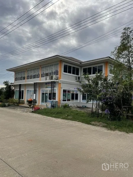 Warehouse for rent or sale in Pathum Thani - Corner view of a two-story office block with landscaped verge.