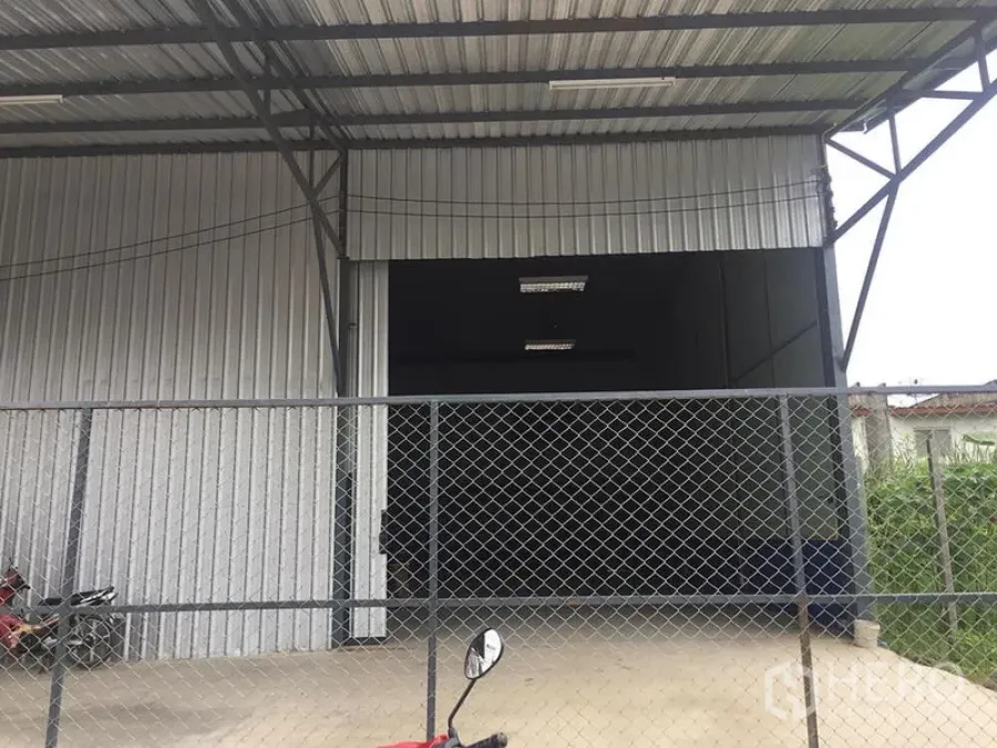 Warehouse for rent in Lat Krabang, Bangkok - Covered loading bay with chain-link fence in front of steel-clad warehouse.