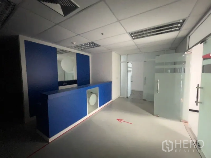 Office Space for rent - Blue reception desk facing frosted glass partitions and corridor.